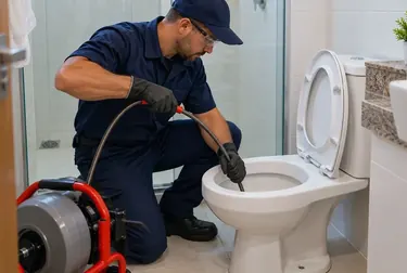 Profissional realizando desentupimento de vaso sanitário, utilizando equipamentos específicos.
